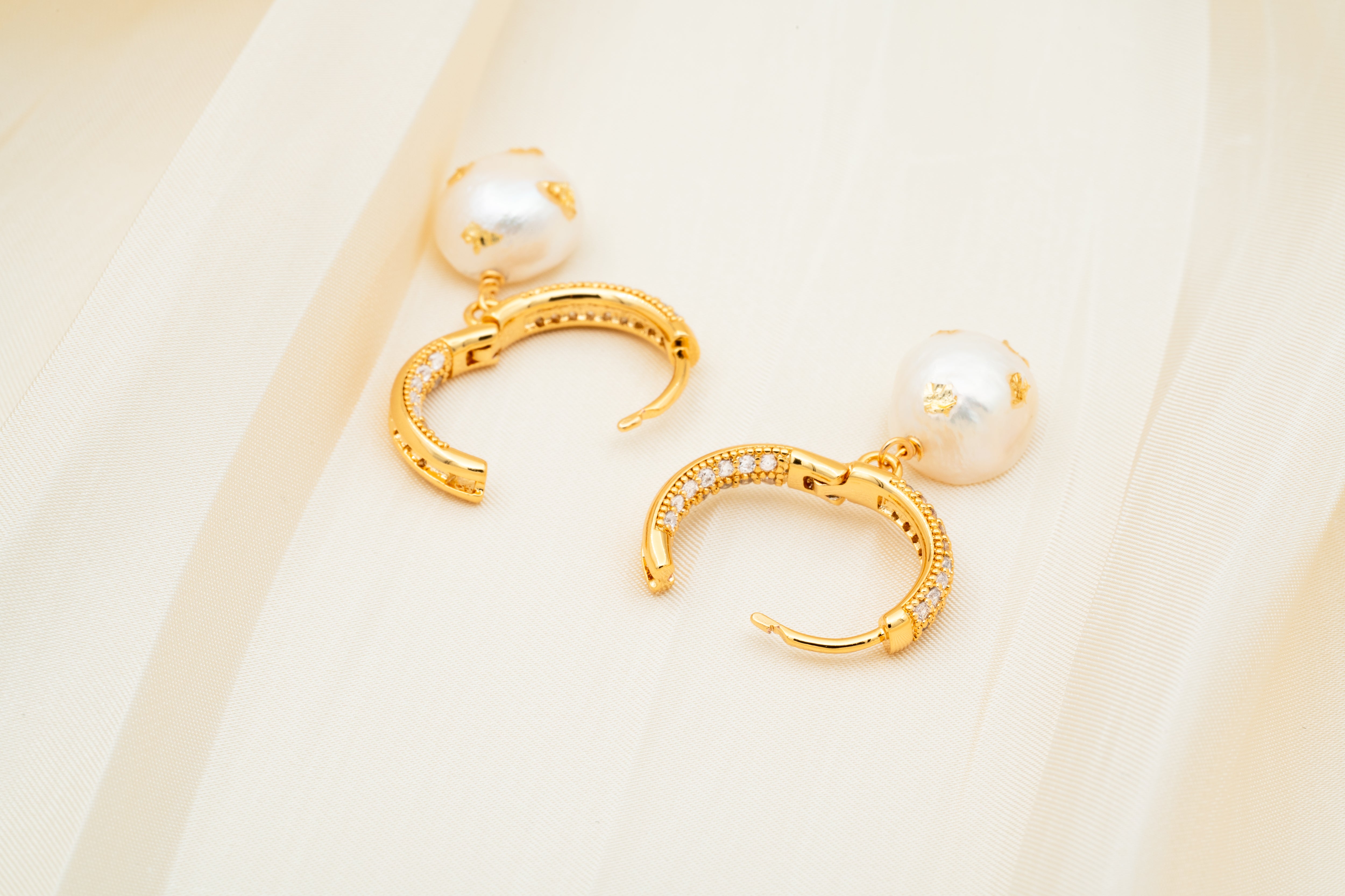 Close-up of gold geometric hoop earrings with pearl drops – minimalist fashion jewelry